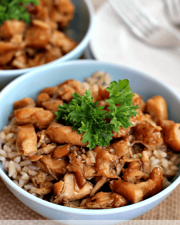 Two blue bowls of crock pot chicken teriyaki on rice