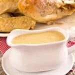 A white gravy boat of easy homemade gravy in front of a cooked turkey