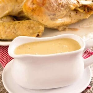 A white gravy boat of easy homemade gravy in front of a cooked turkey