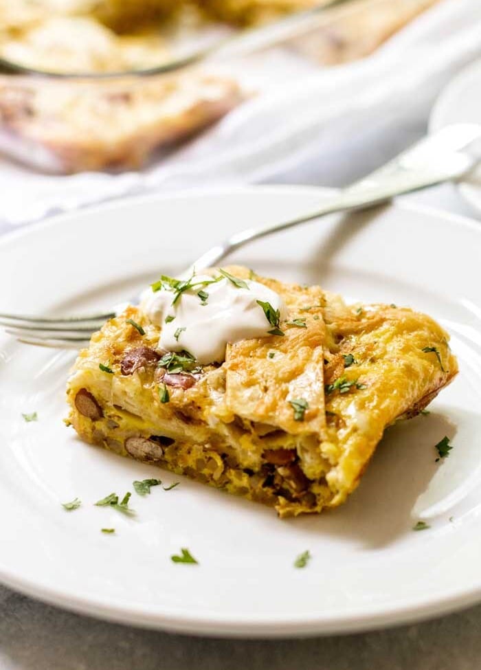 Green chile breakfast enchilada casserole on a white plate with a fork