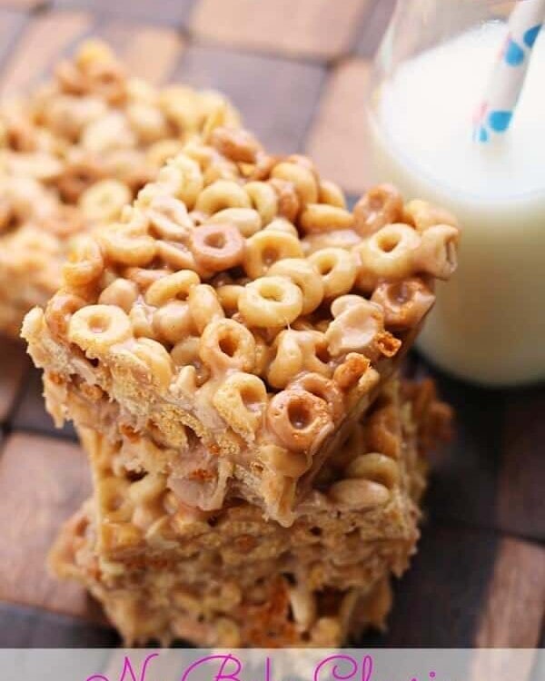 Astack of no bake cheerio peanut butter bars on a wood board with a glass of milk