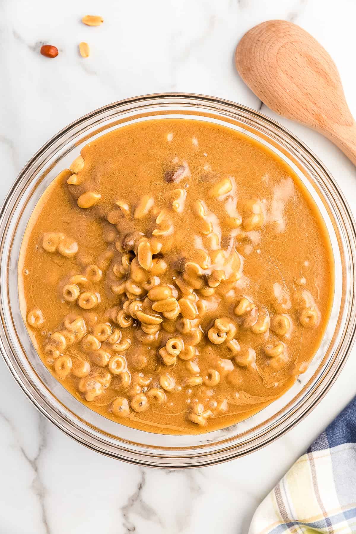 Cheerios and peanuts in glass bowl covered with peanut butter sauce