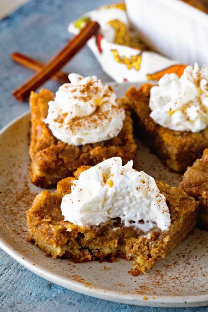 Pumpkin Bars on a plate with the front one having a bite taken out of it.