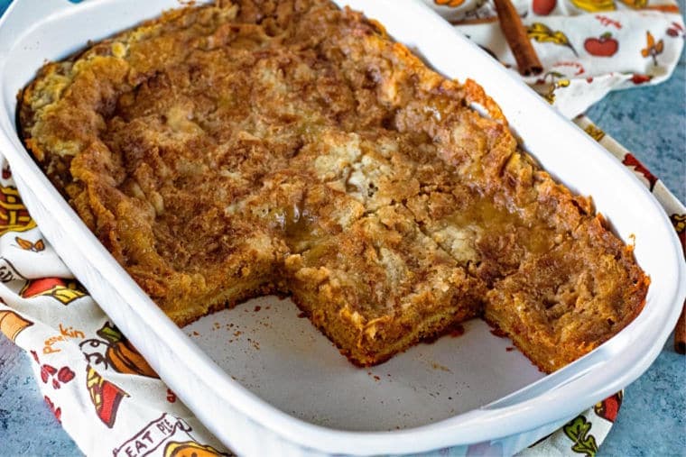 A white baking dish with pumpkin dessert in it. Several pieces are missing.