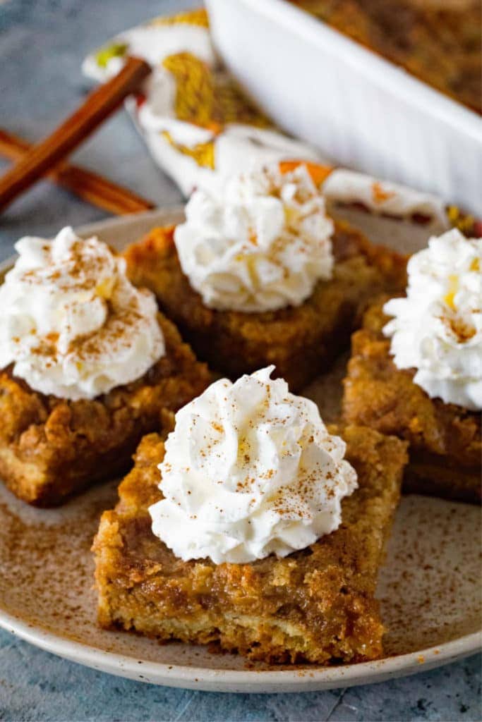 Pumpkin Dessert Bars on plate with whipped cream on top and cinnamon.