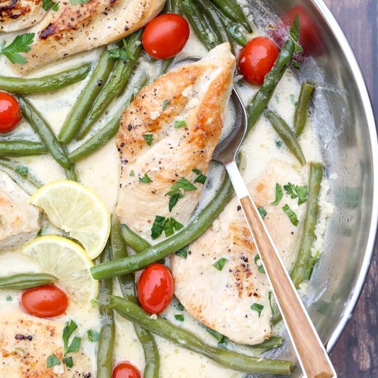 Skillet pan of chicken breasts, green beans, cherry tomatoes, lemon slices, and sauce