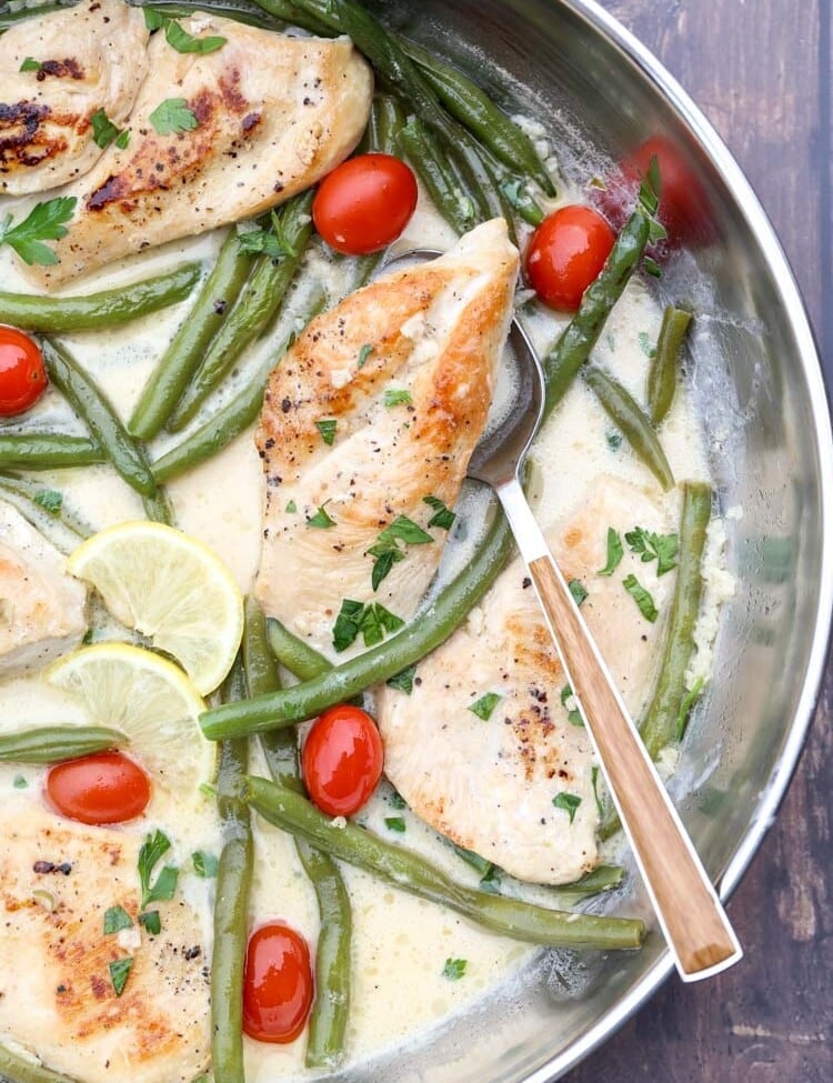 Chicken and Green Beans in Skillet with sauce, lemon slices, and cherry tomatoes