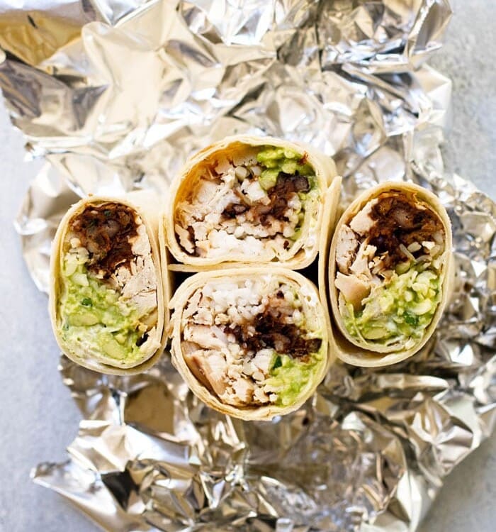 Four halves of chipotle black bean chicken burritos with the cut side facing up on a piece of tin foil