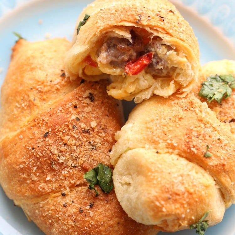 Three Crescent Rolls with Sausage, Peppers, Egg and Cheese Filling on a blue plate