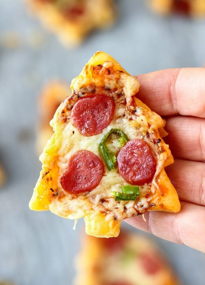 Hand holding a mini christmas tree shaped pepperoni pizza