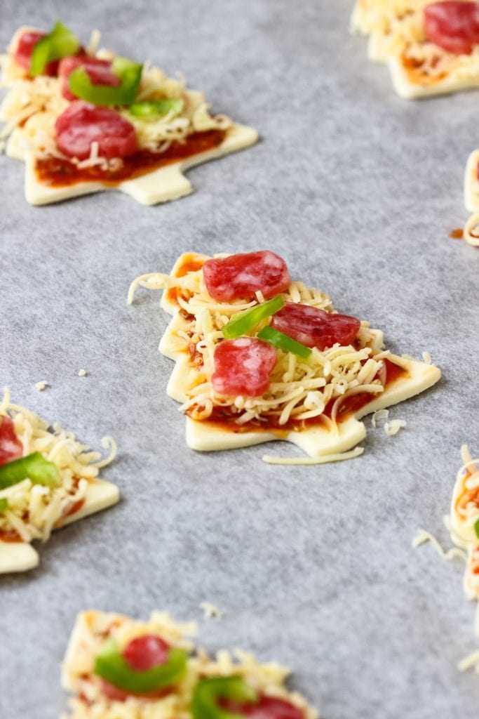 Christmas tree shaped pizzas uncooked on a baking sheet lined with parchment paper