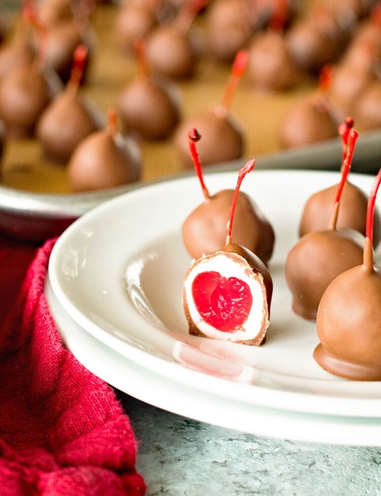 Chocolate covered cherries on a plate and on a baking sheet