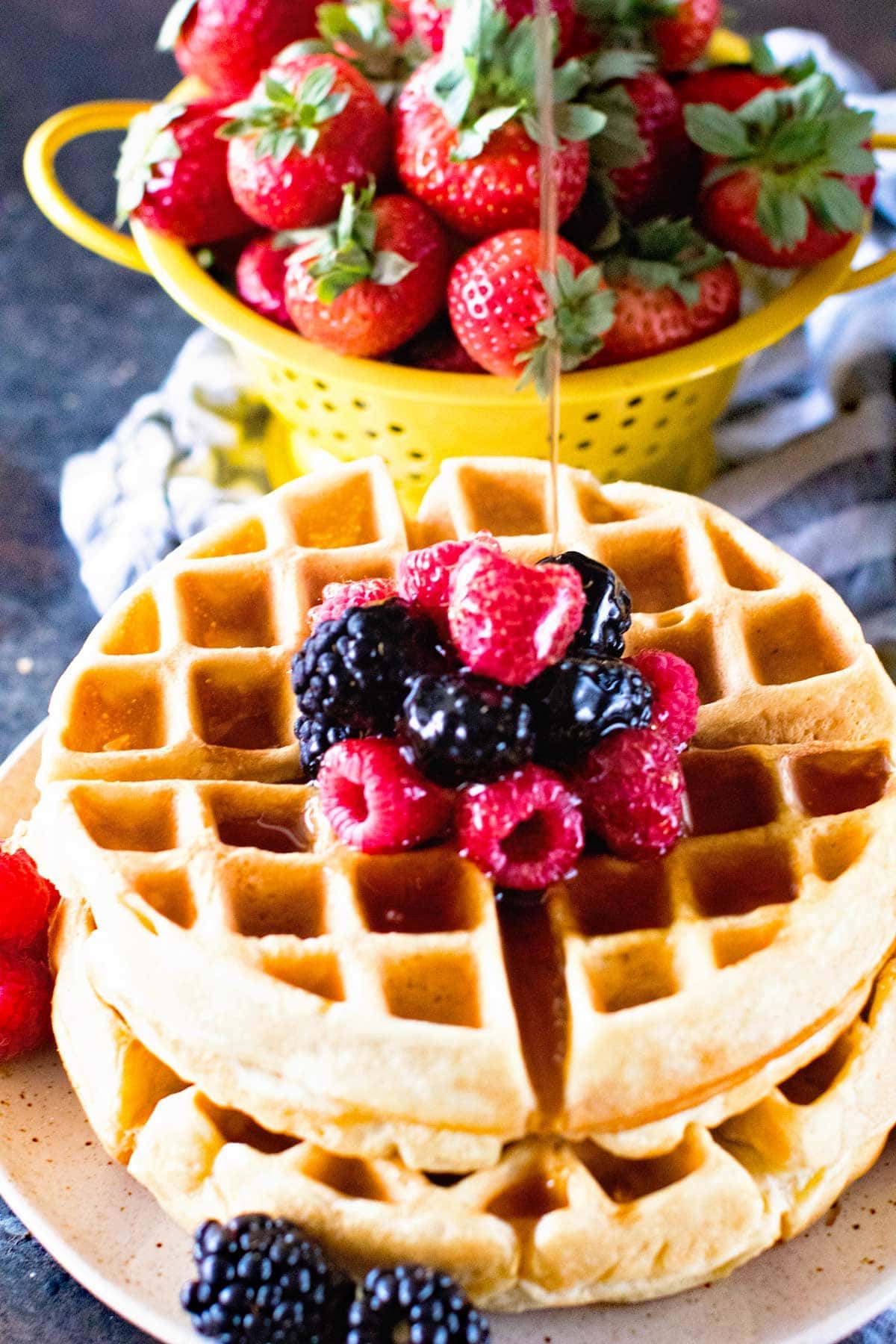 fluffy waffle recipe topped with fruit and drizzled with syrup.