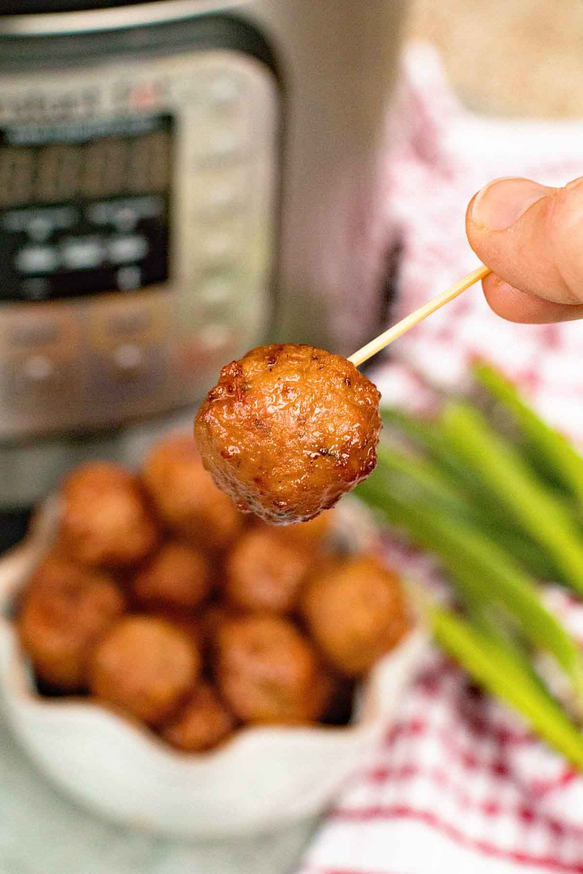 A toothpick holding a cooked grape jelly meatball