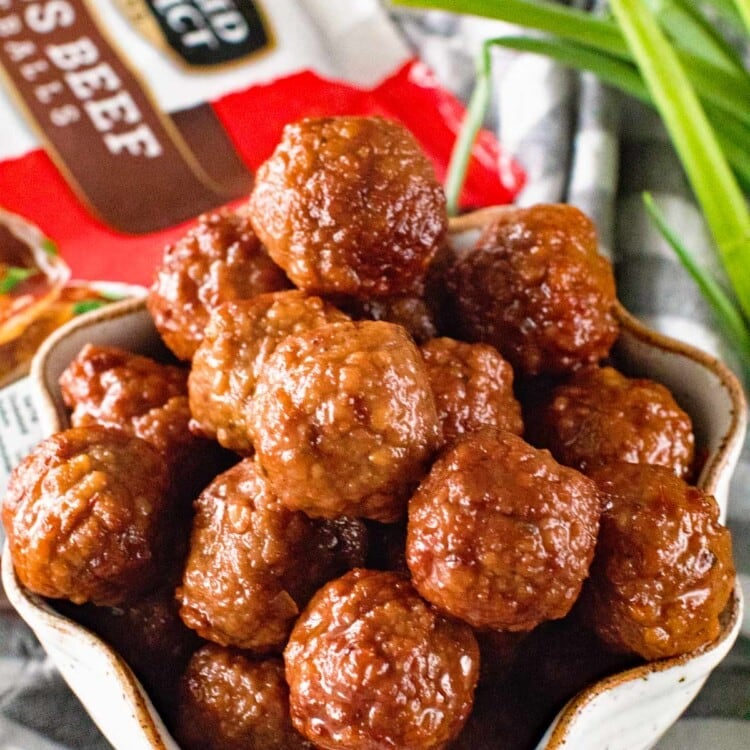 Meatballs with Grape Jelly and Chili Sauce in a white bowl on a grey and white striped towel