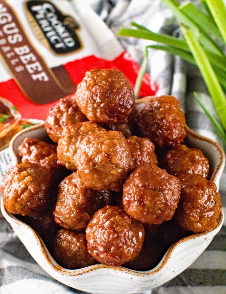 Meatballs with Grape Jelly and Chili Sauce in a white bowl on a grey and white striped towel