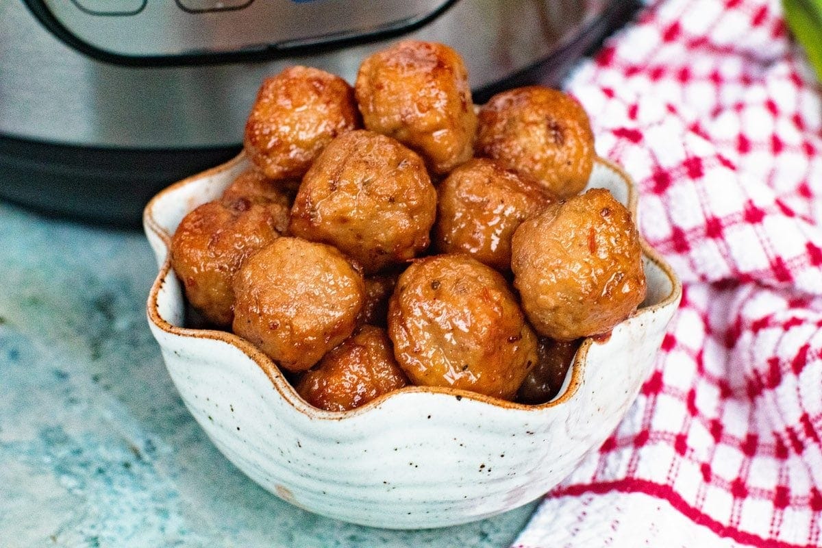 Grape Jelly Meatballs in a bowl in front of Instant Pot