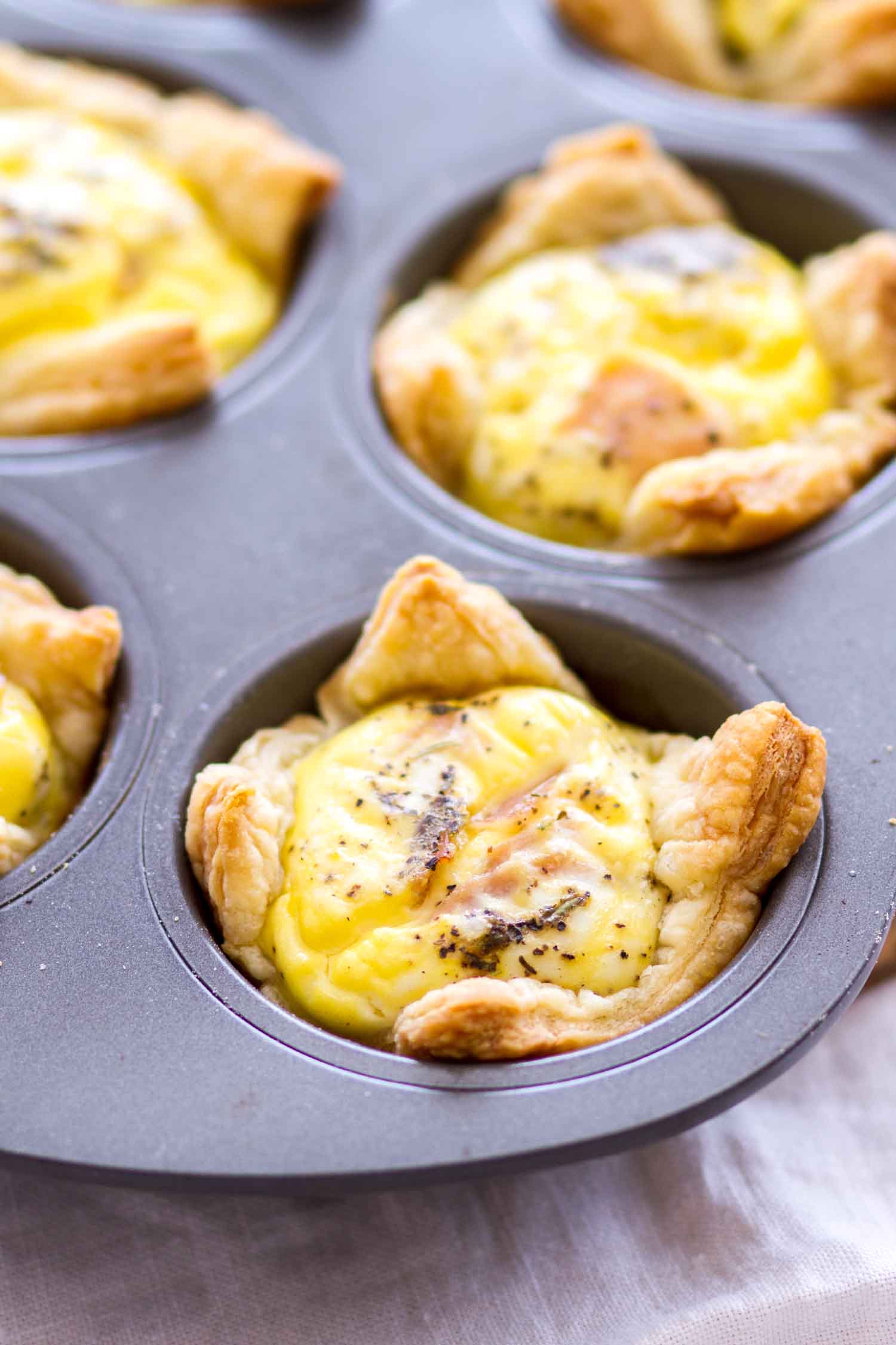 Quiche cups with ham and cheddar cheese in a muffin tin