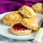 Classic English Scones on a white plate one cut in half with jam