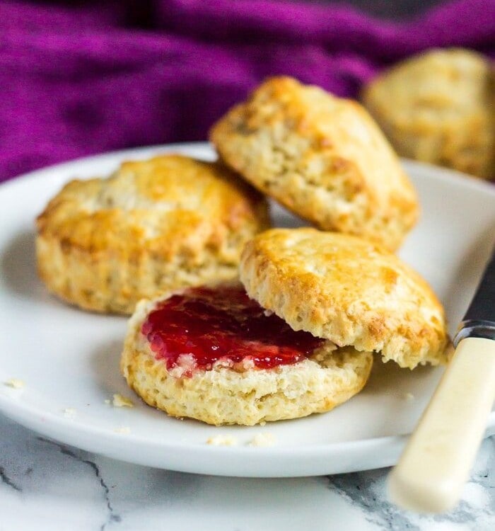 Classic English Scones on a white plate one cut in half with jam