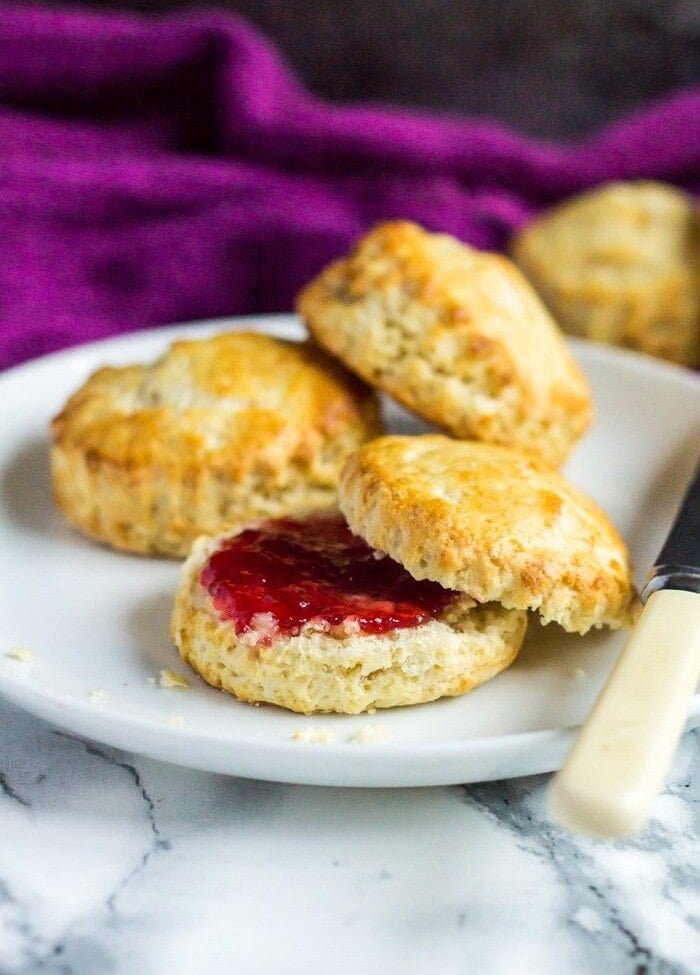 Classic English Scones on a white plate one cut in half with jam