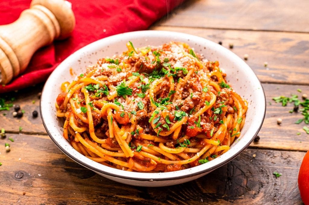 Bowl of spaghetti with a red napkin in background.