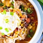 Chicken Taco Soup in a white bowl with sour cream and green onions on top