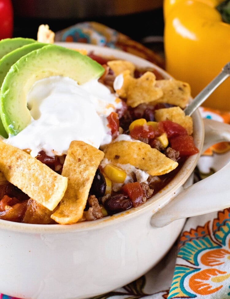Taco Soup in a white bowl topped with fritos, sour cream, and avocado slices