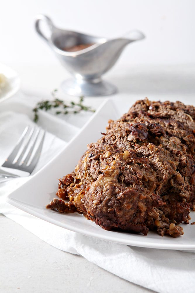 French Onion Meatloaf, sitting on a white platter, sliced and ready for eating