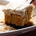 Slice of carrot cake on a spatula being lifted out of a cake pan