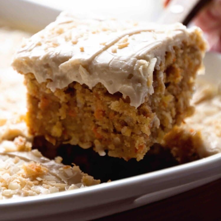 Slice of carrot cake on a spatula being lifted out of a cake pan