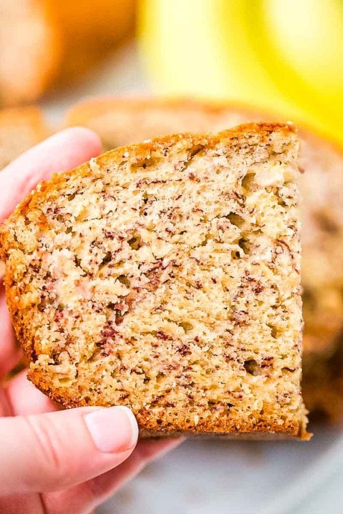 A hand holding a half slice of banana bread