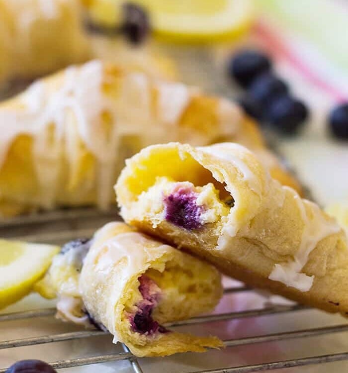 Lemon blueberry cheesecake crescent rolls on a cooling rack with the front one ripped in half