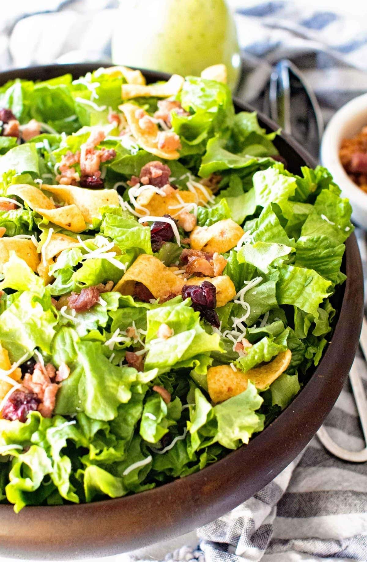 Frito Salad in brown bowl with a blue striped napkin in background