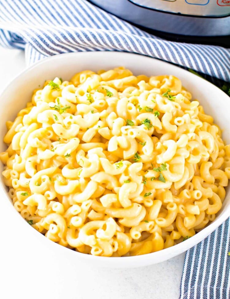 Pressure cooker macaroni and cheese in a white bowl in front of a pressure cooker