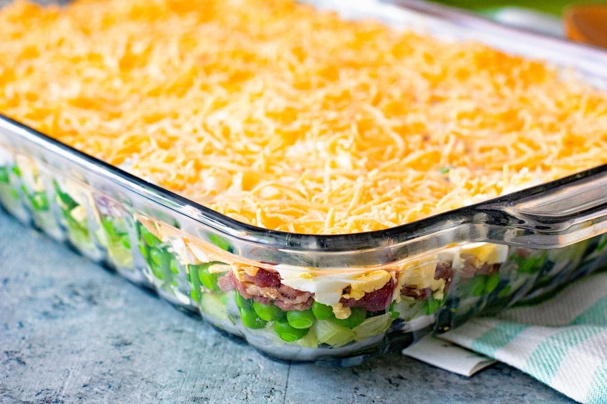 Seven Layer Salad in a clear glass baking dish sitting on a gray counter top
