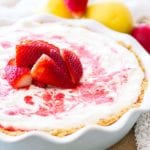 A strawberry lemon icebox pie on a burlap place mat with strawberries and lemons