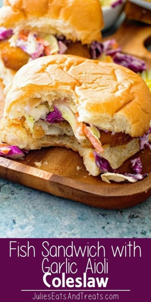 Fish sandiwch with garlic aioli coleslaw on cutting board with a bite missing