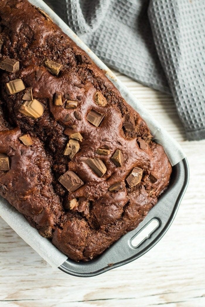 Overhead image of baked chocolate banana bread in loaf pan with chocolate chunks on top of bread