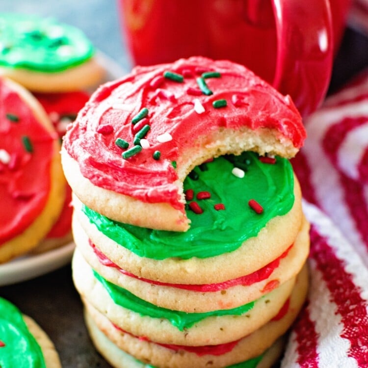 A stack of perfect sugar cookies with red and green frosting in front of a red mug