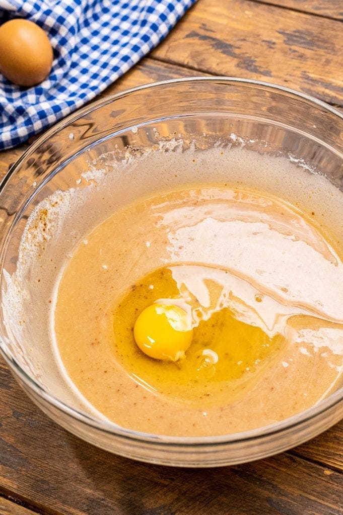 Glass bowl with batter and an egg before mixing.