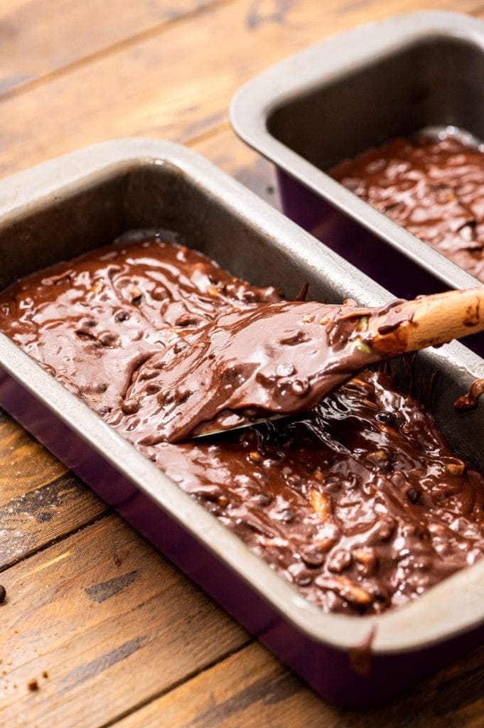 Smoothing chocolate zucchini bread batter into a pan with spatula