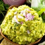 Homemade Guacamole in bowl next to an onion and tortilla chips