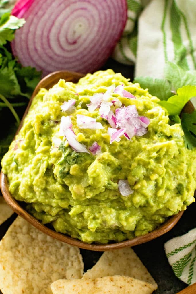 Brown bowl with guacamole topped with chopped red onion