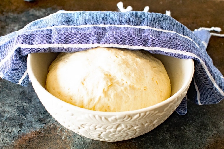 Making Pizza Dough can't get any easier than this! If you've been scared to try to make homemade pizza dough try this recipe. It comes together quickly and is perfectly thick, chewy and delicious! Easy Pizza Dough in White Bowl