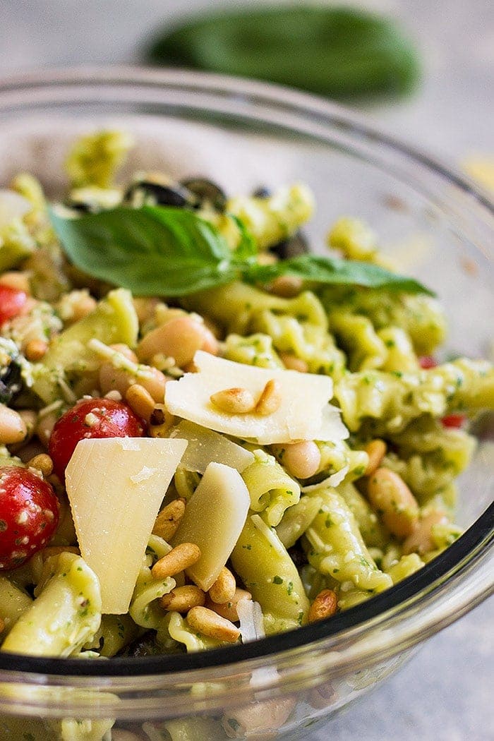 Close up of cold pasta salad with tomatoes, cheese, pine nuts.