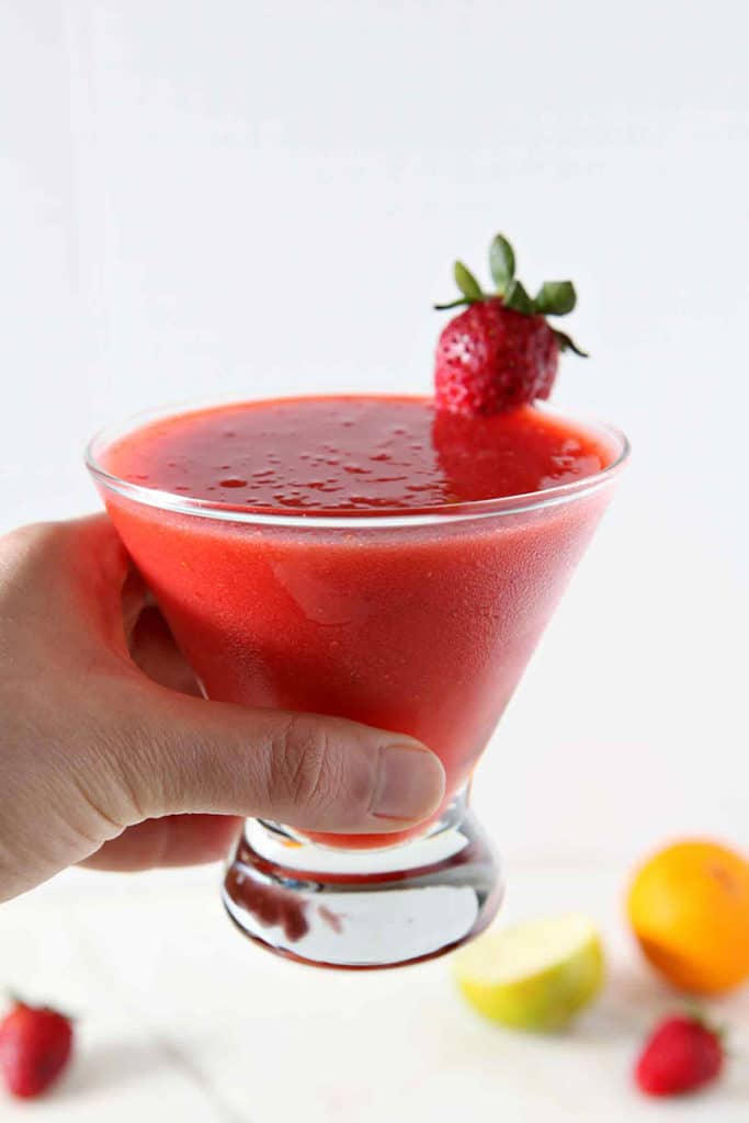 A woman holds a Strawberry Virgin Margarita in her hand before drinking.