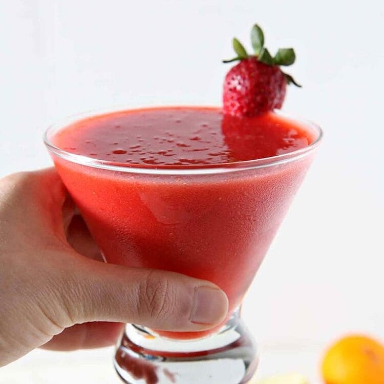 A woman holds a Strawberry Virgin Margarita in her hand before drinking.