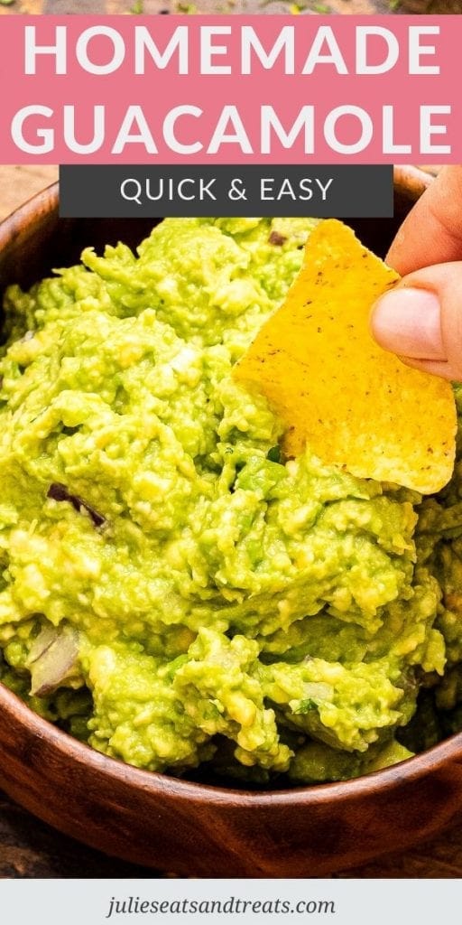 Hand holding a tortilla chip and dipping it into guacamole