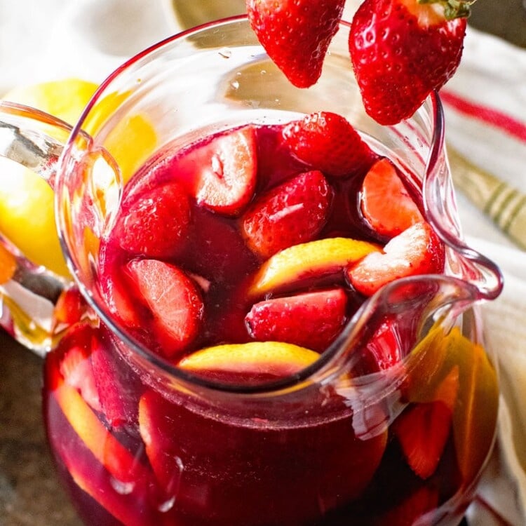 easy sangria in glass pitcher with strawberries and lemon slices in it